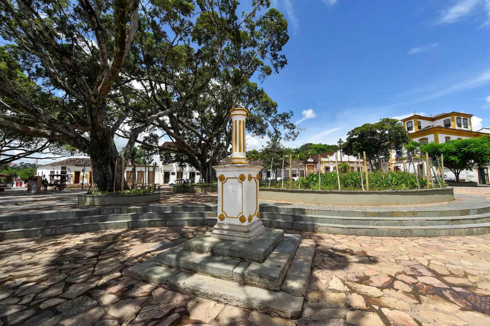 Largo das Forras, em Tiradentes, com cruzeiro de pedra e árvores ao fundo