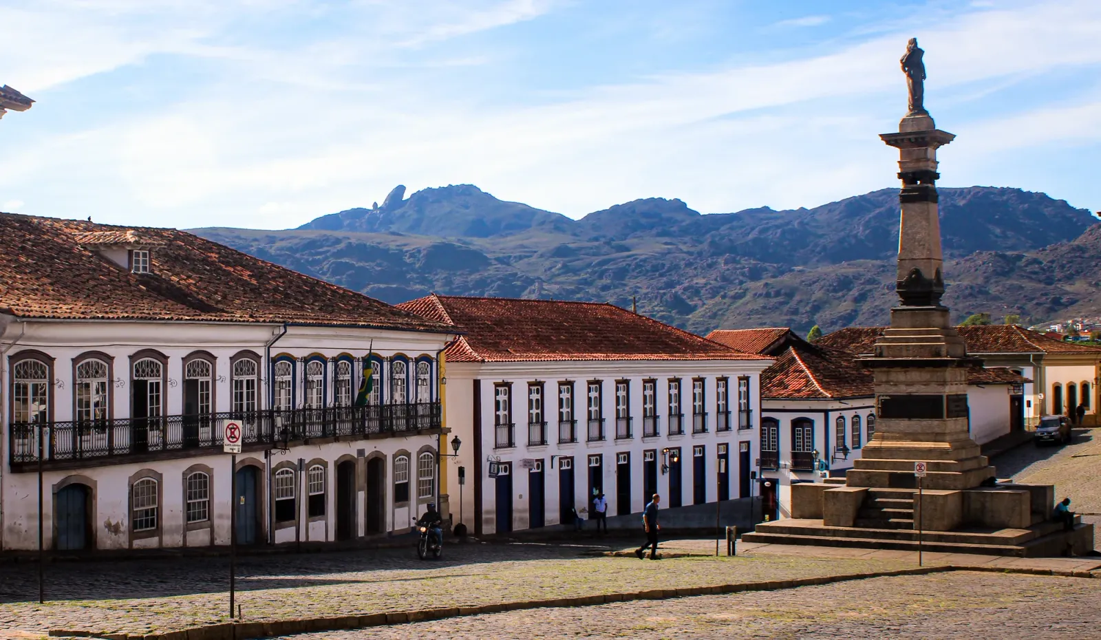 Praça de Ouro Preto com monumento e casarões coloniais, com a serra ao fundo