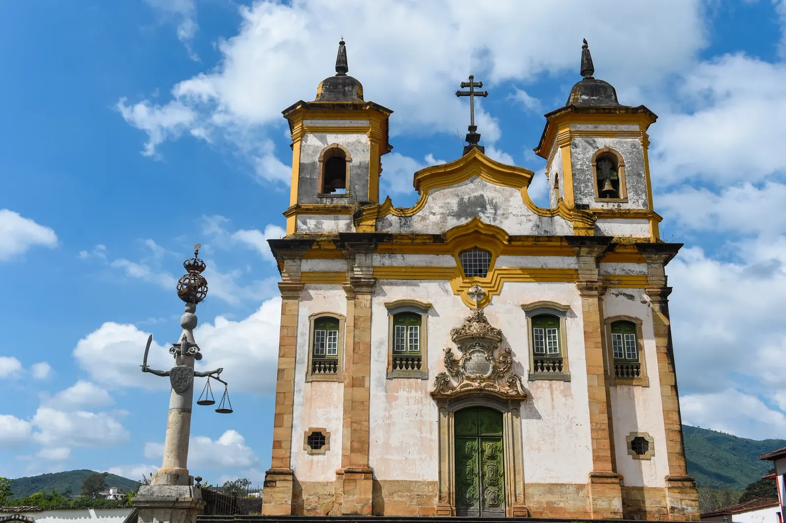 Fachada da Igreja de São Francisco de Assis, em Mariana, com duas torres e o pelourinho em primeiro plano